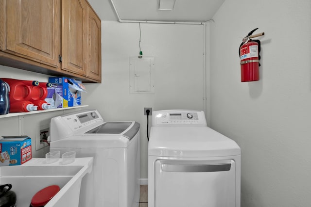 clothes washing area featuring cabinets, washing machine and dryer, electric panel, and sink