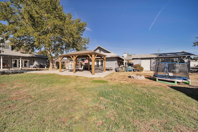 back of house with a gazebo, a yard, and a trampoline