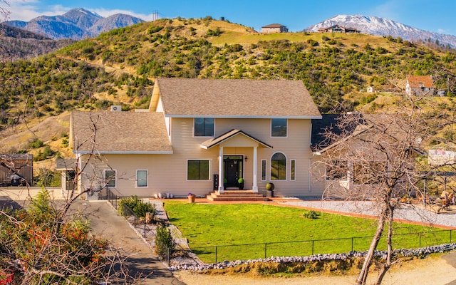 view of front of home with a mountain view and a front lawn