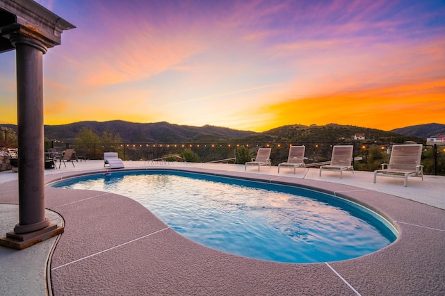 pool at dusk with a mountain view and a patio