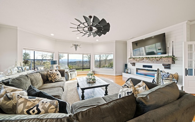 living room featuring ceiling fan, light wood-type flooring, and ornamental molding