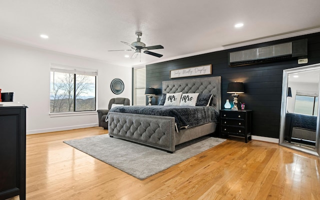 bedroom with ceiling fan, light hardwood / wood-style floors, crown molding, and a wall mounted AC