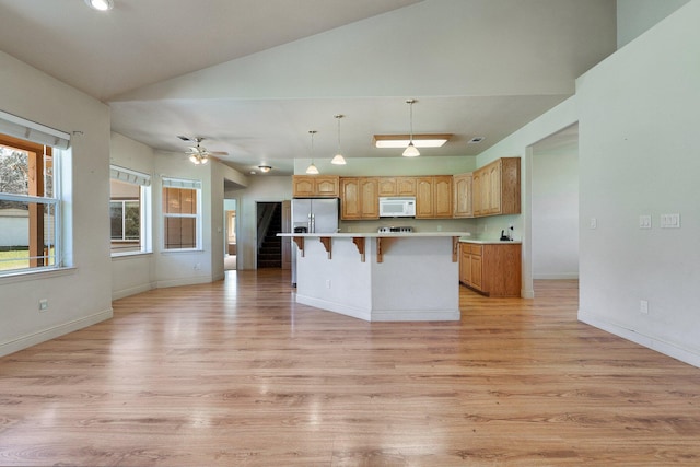 7899 Elmers Way, Shingletown, CA 96088 - kitchen featuring white microwave, vaulted ceiling, a breakfast bar, stainless steel fridge, and light countertops