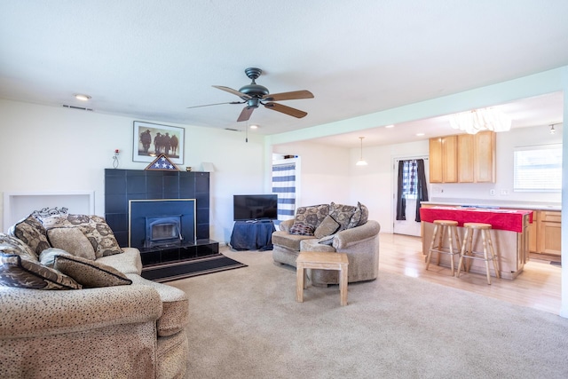 living area with visible vents, light colored carpet, light wood-style flooring, and a ceiling fan