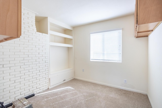 interior space with built in shelves, brick wall, baseboards, and carpet floors