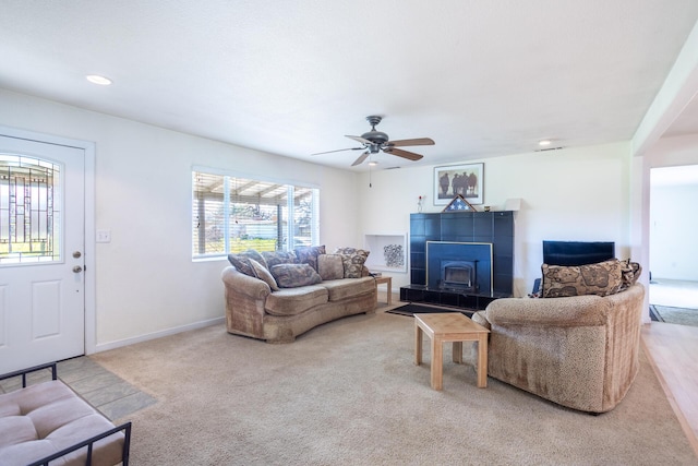 living room featuring baseboards, recessed lighting, ceiling fan, a tile fireplace, and light carpet