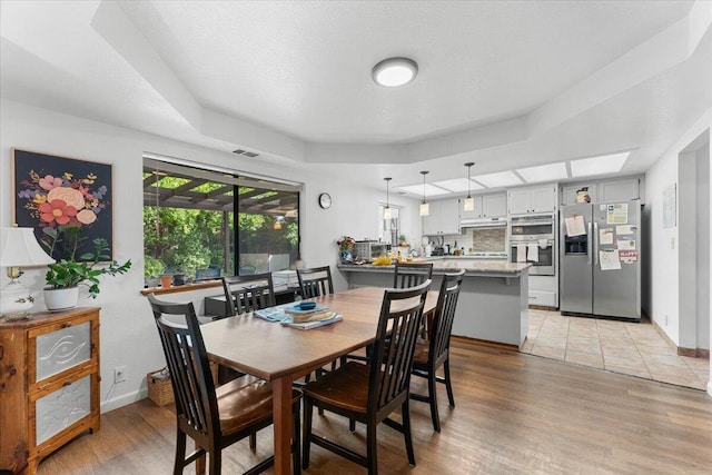 711 Teakwood Dr, Redding, CA 96003 - dining room with light wood-type flooring, a tray ceiling, and baseboards