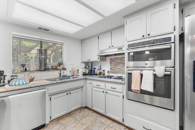 711 Teakwood Dr, Redding, CA 96003 - kitchen with stainless steel appliances, under cabinet range hood, tasteful backsplash, and light countertops