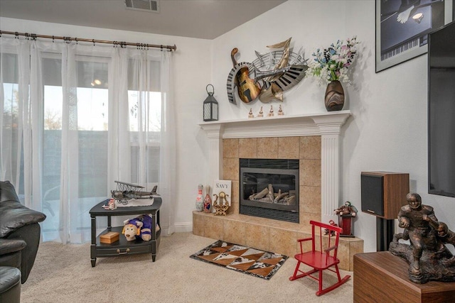 carpeted living room with a tiled fireplace