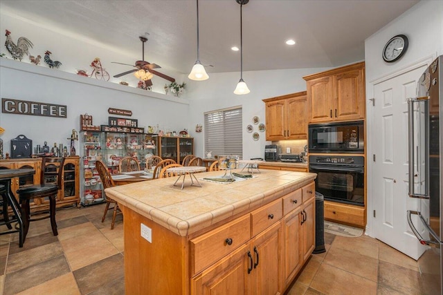 kitchen featuring ceiling fan, black appliances, a center island, tile counters, and lofted ceiling