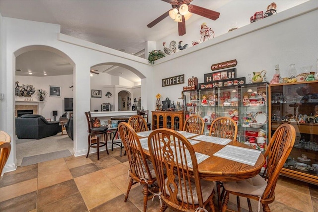 dining space with ceiling fan and a tile fireplace