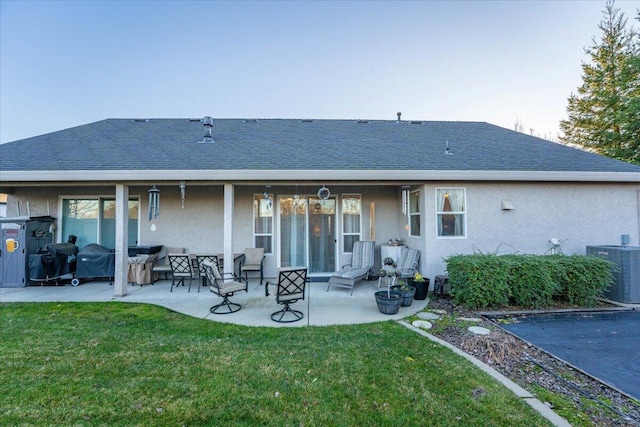 rear view of property with central air condition unit, a patio area, and a lawn