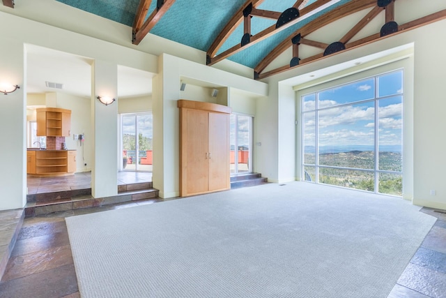 interior space with beamed ceiling, plenty of natural light, sink, and high vaulted ceiling