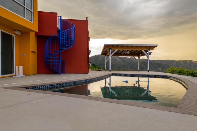 pool at dusk with a mountain view and a patio area