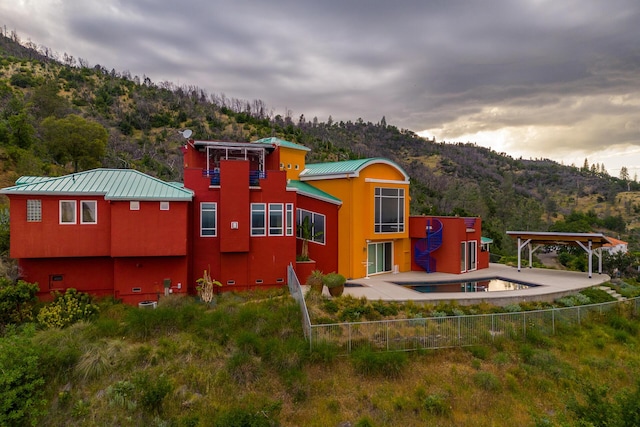 rear view of property featuring a mountain view, a swimming pool, and a patio