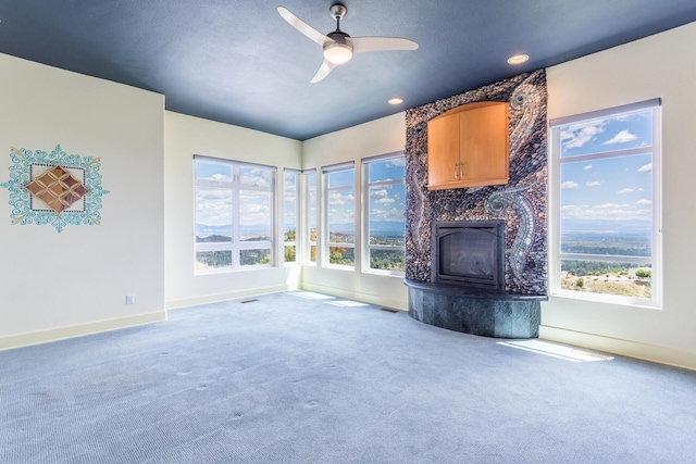 unfurnished living room featuring a fireplace, carpet, and ceiling fan