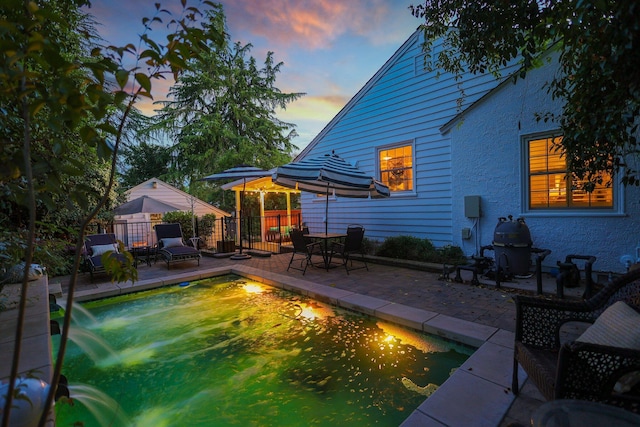 pool at dusk featuring a patio and pool water feature