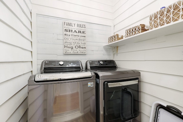 laundry room with washing machine and dryer and wooden walls