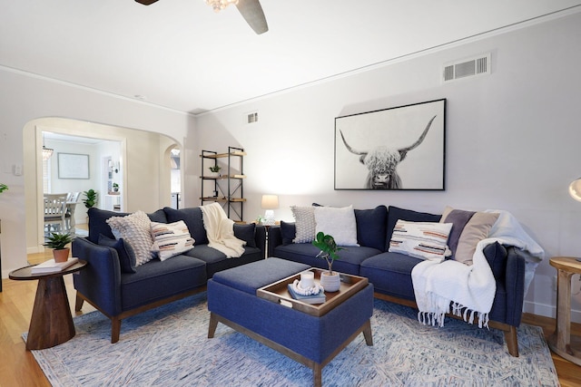 living room featuring light wood-type flooring, ceiling fan, and ornamental molding