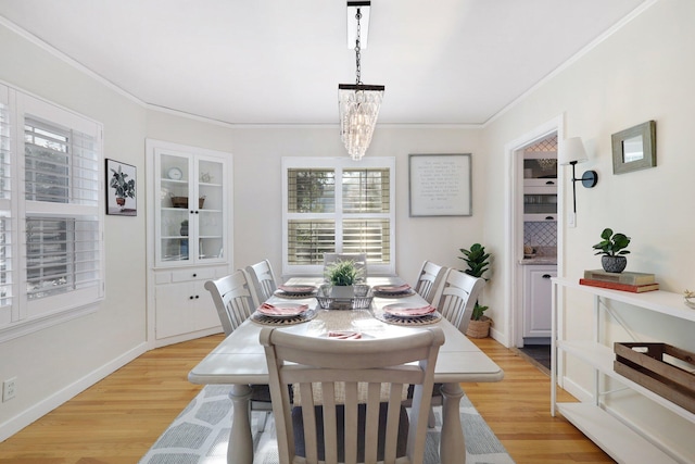 dining space with light hardwood / wood-style flooring, an inviting chandelier, and ornamental molding