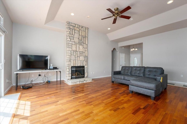 living room featuring a fireplace, hardwood / wood-style floors, and ceiling fan with notable chandelier