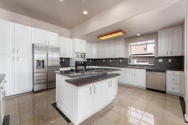 kitchen featuring sink, decorative backsplash, a kitchen island, white cabinetry, and stainless steel appliances