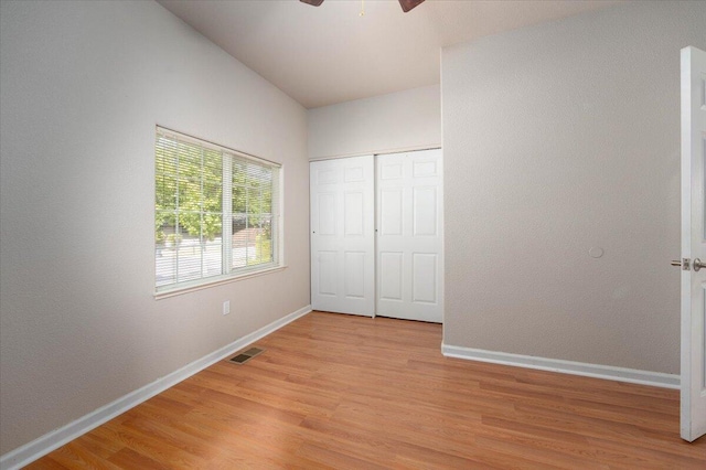 unfurnished bedroom with a closet, light hardwood / wood-style flooring, ceiling fan, and lofted ceiling