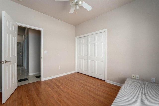 unfurnished bedroom featuring ceiling fan, wood-type flooring, and a closet