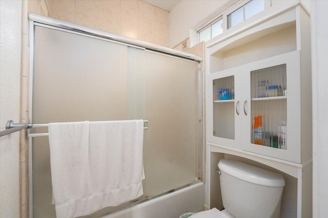 bathroom featuring enclosed tub / shower combo and toilet