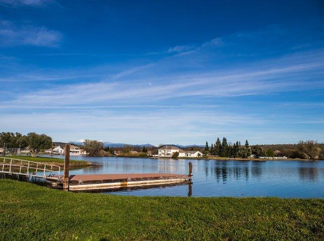 view of dock with a water view and a lawn