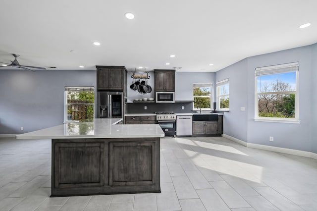 kitchen with sink, stainless steel appliances, tasteful backsplash, a center island with sink, and dark brown cabinets