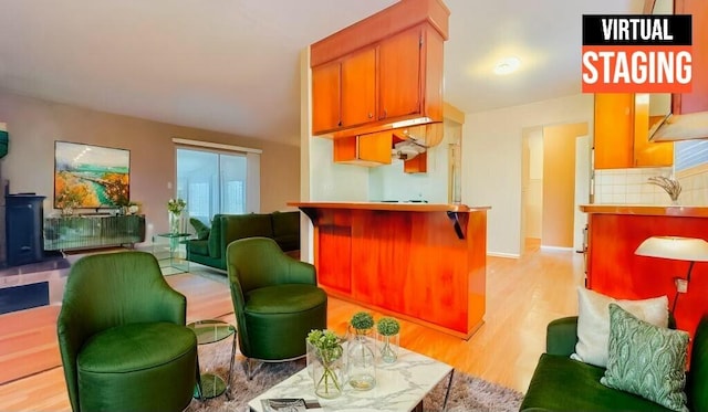 kitchen with decorative backsplash, light hardwood / wood-style floors, a kitchen breakfast bar, and sink