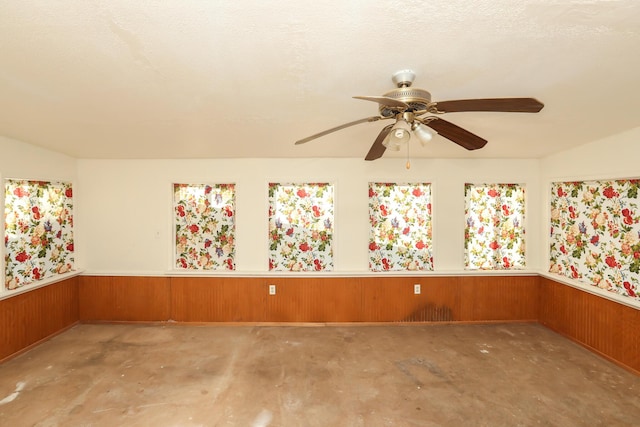 spare room featuring ceiling fan and wood walls