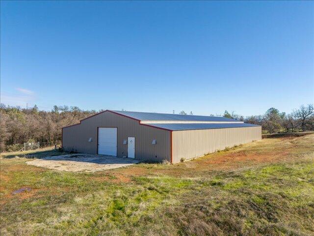 rear view of property featuring a garage, an outbuilding, and a yard