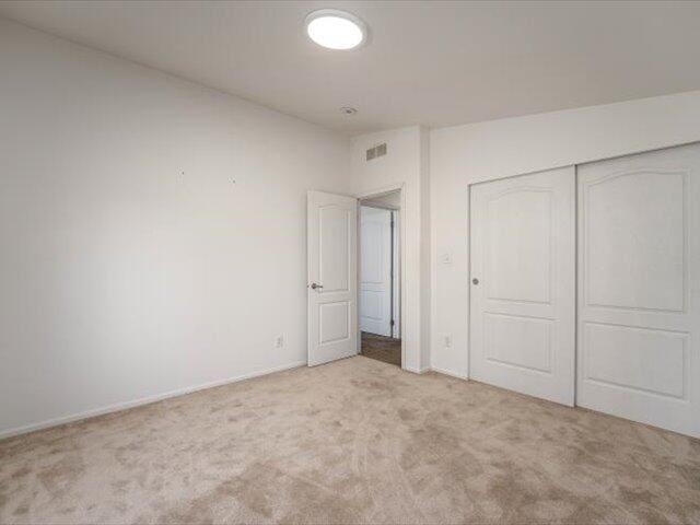 unfurnished bedroom with light carpet and a closet