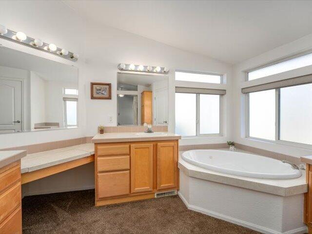 bathroom with a bathing tub, vanity, and lofted ceiling