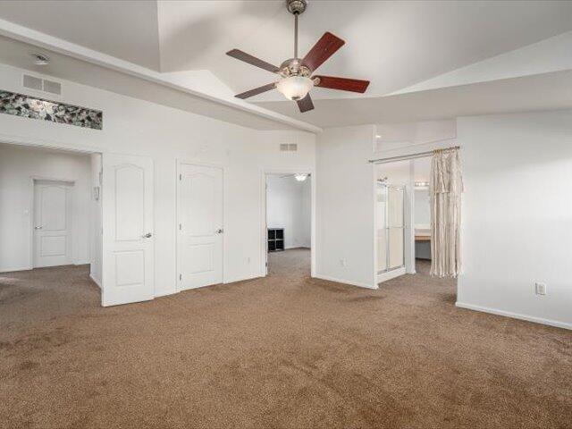 unfurnished bedroom with carpet, ensuite bathroom, ceiling fan, and lofted ceiling