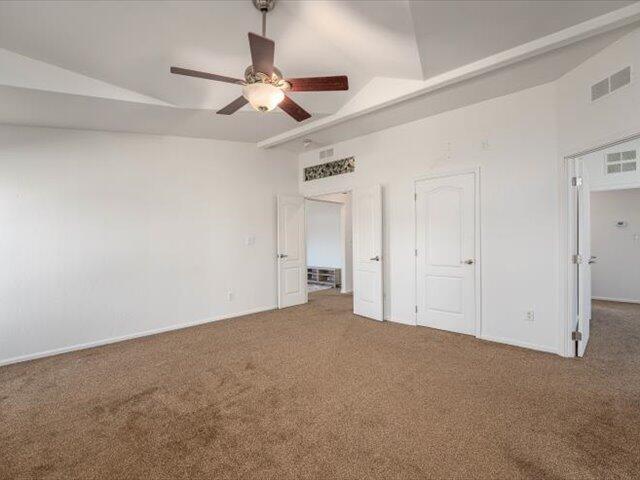 unfurnished bedroom with carpet flooring, ceiling fan, and vaulted ceiling