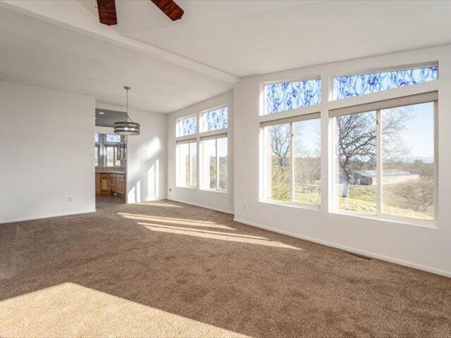 unfurnished sunroom featuring ceiling fan and a healthy amount of sunlight