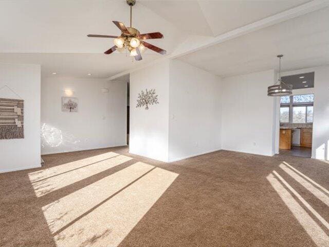 unfurnished living room with ceiling fan with notable chandelier, carpet floors, and lofted ceiling