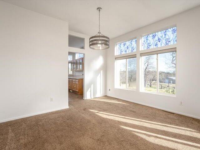 unfurnished dining area with plenty of natural light, carpet, and a chandelier