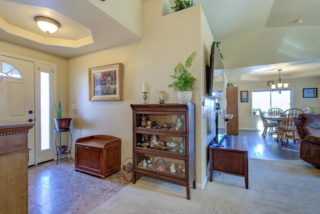 foyer featuring an inviting chandelier and a tray ceiling