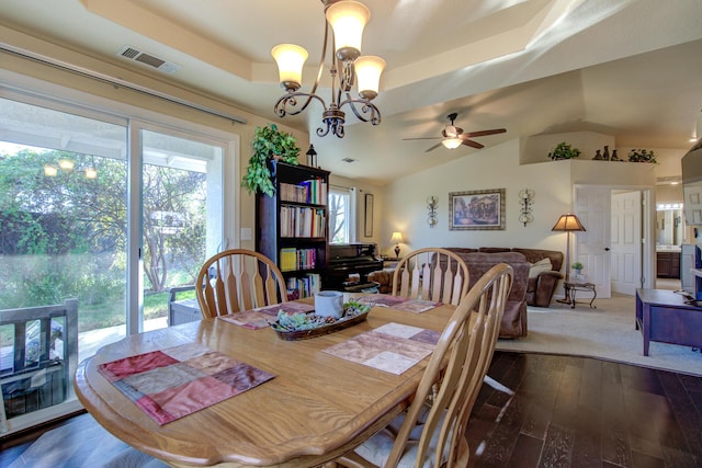 dining area featuring vaulted ceiling, a tray ceiling, ceiling fan with notable chandelier, and hardwood / wood-style floors