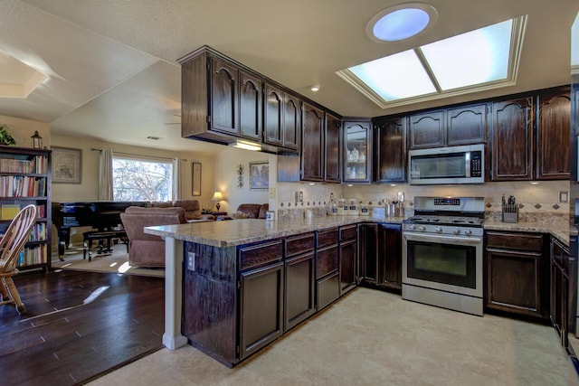 kitchen featuring stainless steel appliances, dark brown cabinets, decorative backsplash, and kitchen peninsula