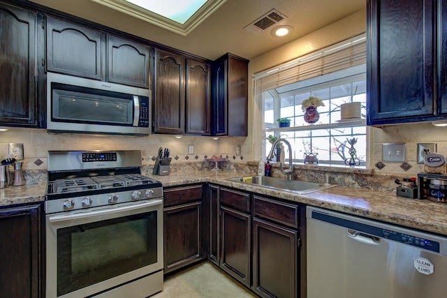 kitchen with tasteful backsplash, dark brown cabinetry, appliances with stainless steel finishes, and sink