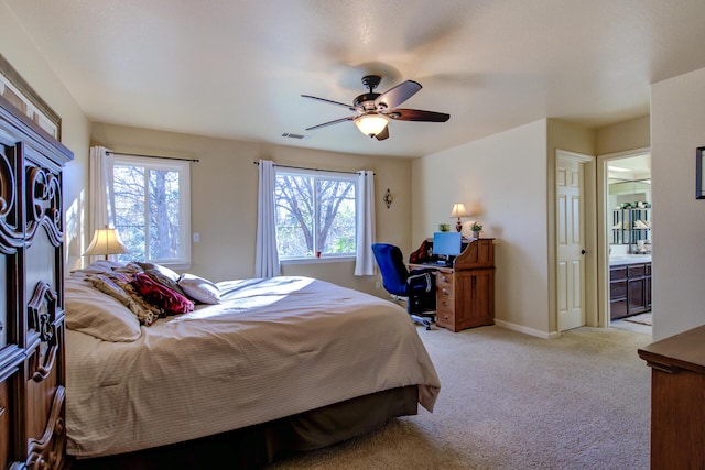 bedroom featuring multiple windows, connected bathroom, light colored carpet, and ceiling fan