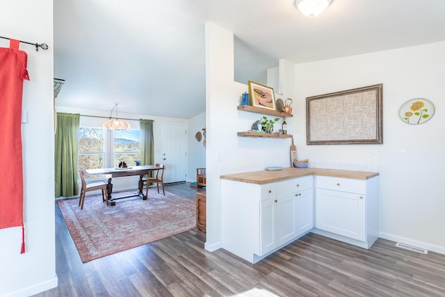 kitchen featuring wood counters, dark hardwood / wood-style floors, white cabinetry, and hanging light fixtures