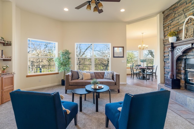 carpeted living room featuring ceiling fan with notable chandelier and a tile fireplace