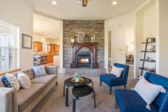 carpeted living room featuring a stone fireplace and plenty of natural light