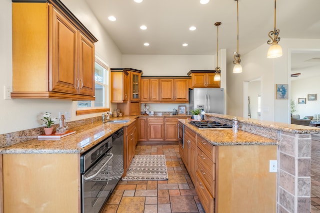 kitchen with sink, appliances with stainless steel finishes, decorative light fixtures, a kitchen island, and light stone counters